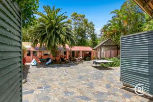 a patio with a table and a palm tree at Dolphins Backpackers in Sunshine Beach