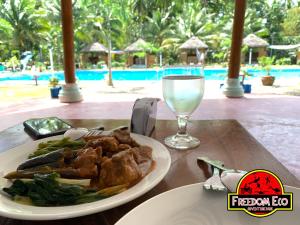a table with a plate of food and a glass of wine at Freedom Eco Adventure Park powered by Cocotel in Boac