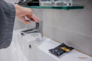 a person is reaching for a faucet on a sink at Amamas Boutique Hotel Kuching in Kuching +92 photos