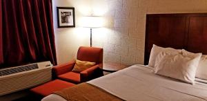 Habitación de hotel con cama y silla en Cedar Inn Motel, en Cavalier