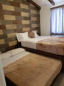 a bedroom with two beds and a wooden wall at Cabaña Eucalipto 32 in Mazamitla