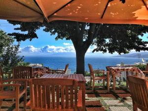 a table and chairs with an umbrella and the ocean at Capri Wine Hotel in Capri