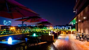 a rooftop patio with tables and umbrellas at night at Hotel Coka Chuansha Metro - Shanghai PVG Airport in Shanghai