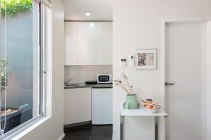 een keuken met witte kasten en een raam bij Stunning Views To Beat Lockdown Blues in Sydney