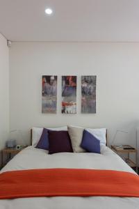 a bedroom with a bed with three paintings on the wall at Stunning Views To Beat Lockdown Blues in Sydney