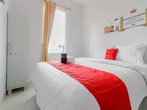 un letto rosso e bianco in una camera bianca di RedDoorz Plus near Taman Rasuna Menteng a Giacarta