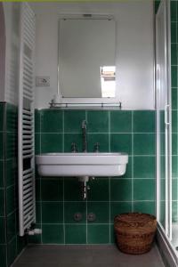 een groene betegelde badkamer met een wastafel en een spiegel bij Punta Del Corno Agriturismo in San Felice del Benaco