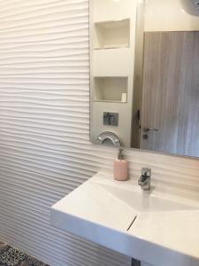 Un baño blanco con lavabo y espejo. en Turquoise and Magenta Apartments, en Sofía 9 fotos más