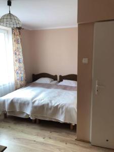 una camera da letto con un letto con lenzuola bianche e una finestra di Willa Adamów a Mielno