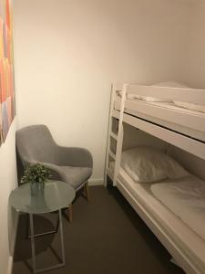 Pokój z 2 łóżkami piętrowymi, krzesłem i stołem w obiekcie Ferienwohnung Reuter - Am Meer w mieście Bad Zwischenahn