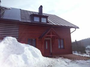 um monte de neve em frente a uma cabana de madeira em Chata Slunečná louka em Cerný Dul