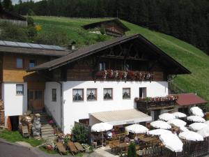 ein Gebäude mit Tischen und Sonnenschirmen davor in der Unterkunft Gasthaus Oberkirn in Schenna