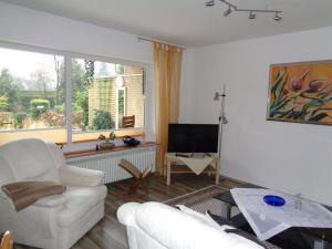 a living room with a white couch and a television at Ferienhaus "Pusteblume" in Bad Zwischenahn