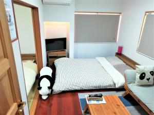Panda Stay Okayama في أوكاياما: غرفة نوم فيها سرير وكلب