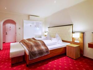 a bedroom with a large bed and a red carpet at Naturhotel Rügers Forstgut in Mespelbrunn