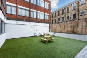 a patio with a wooden picnic table and two buildings at Stylish Modern City Centre Apartment in Gloucester