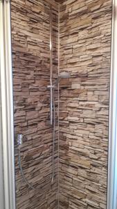 a shower in a bathroom with a stone wall at Pension Dreiländereck in Birx