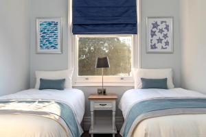 two twin beds in a room with a window at Sandhills Apartments, Mudeford in Christchurch