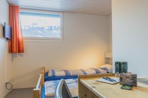 1 dormitorio con cama, escritorio y ventana en Mountain Lodge Backpackercamp en Lenk