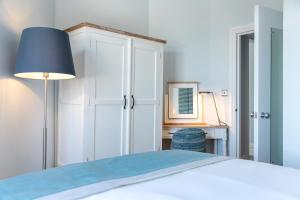 a bedroom with a bed with a lamp and a desk at Sandhills Apartments, Mudeford in Christchurch