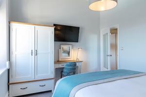 a bedroom with a bed and a cabinet and a desk at Sandhills Apartments, Mudeford in Christchurch