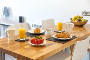 a wooden table with plates of fruit and orange juice at Sandhills Apartments, Mudeford in Christchurch