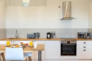 a kitchen with white cabinets and a wooden table at Sandhills Apartments, Mudeford in Christchurch