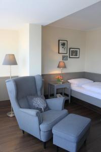 a bedroom with a bed and a chair and a bed and a couch at Hotel An der Linde in Neckarsulm