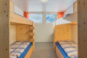 two bunk beds in a room with a window at Mountain Lodge Backpackercamp in Lenk