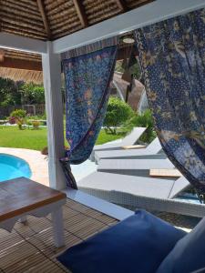 a patio with a pool and a table and curtains at Casa Azzurra in Gili Air