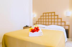 un letto giallo con un asciugamano con fiori di Hotel Villaggio Cala Di Volpe a Capo Vaticano