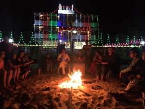 een groep mensen die rond een vuur in het zand zitten bij Blue Lagoon Khavane, Tarkarli- Malvan in Vengurla