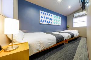 Dos camas en una habitación con una pared azul. en RESI STAY Tsubaki, en Kioto 40 fotos más