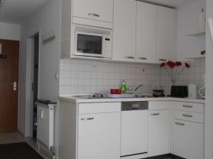 a kitchen with white cabinets and a microwave at Appartement Allgäu-Sonne in Scheidegg