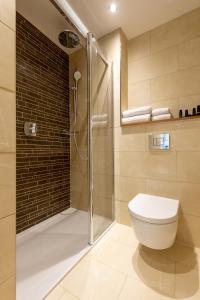 a bathroom with a toilet and a glass shower at Sandhills Apartments, Mudeford in Christchurch