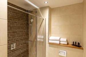 a bathroom with a shower with towels on a shelf at Sandhills Apartments, Mudeford in Christchurch