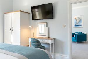 a bedroom with a bed and a desk with a tv on the wall at Sandhills Apartments, Mudeford in Christchurch