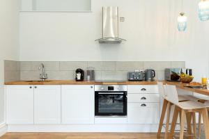 a white kitchen with white cabinets and a sink at Sandhills Apartments, Mudeford in Christchurch