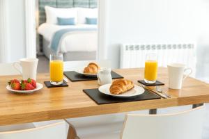 a breakfast table with croissants and fruit and orange juice at Sandhills Apartments, Mudeford in Christchurch