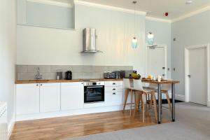 a kitchen with white cabinets and a table with chairs at Sandhills Apartments, Mudeford in Christchurch