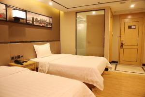 una habitación de hotel con 2 camas y una puerta en 7Days Dongguan Tangxiayin Square Walmart, en Dongguan