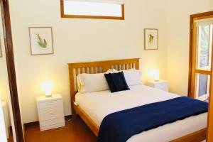 a bedroom with a large bed with two lights on it at Nagoondie Studio in Healesville