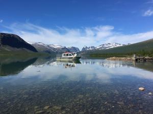 ein Boot auf einem See mit Bergen im Hintergrund in der Unterkunft Enoks i Láddjujávri in Nikkaluokta