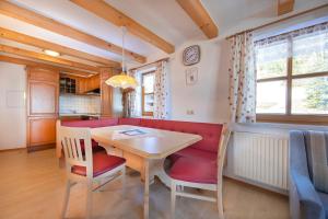 a dining room with a table and a red couch at Peilberghof in Hollersbach im Pinzgau