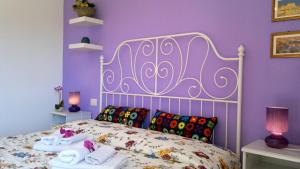 a bedroom with a bed with towels and purple walls at B&B Villa Maria Giovanna in Giardini Naxos
