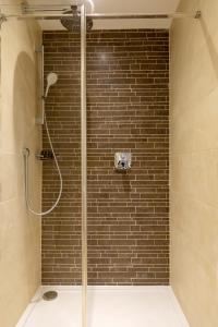 a bathroom with a shower with a brick wall at Sandhills Apartments, Mudeford in Christchurch