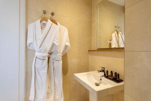 a bathroom with a sink and a white robe at Sandhills Apartments, Mudeford in Christchurch