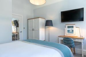 a bedroom with a bed with a desk and a tv at Sandhills Apartments, Mudeford in Christchurch