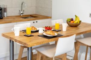 a wooden table with breakfast foods and orange juice at Sandhills Apartments, Mudeford in Christchurch