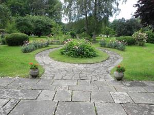 un chemin en pierre dans un jardin avec des pots de fleurs dans l'établissement L atelier d Ombeline, à Bonnal